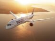 WestJet 787 aircraft inflight over a body of water at sunset.
