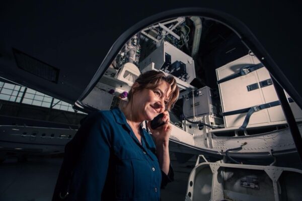 Denise Buklis on her phone in the aircraft hangar.