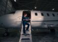 Denise Buklis standing on the stairs of a bizjet in the hangar at night.