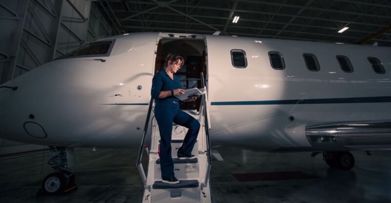 Denise Buklis standing on the stairs of a bizjet in the hangar at night.