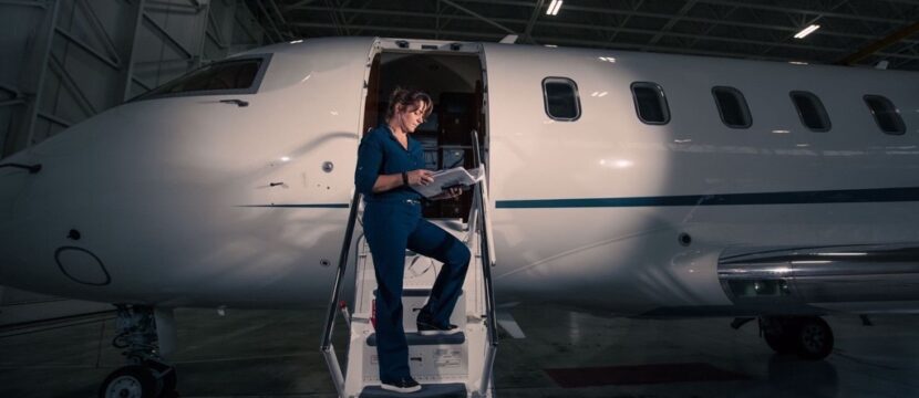 Denise Buklis standing on the stairs of a bizjet in the hangar at night.