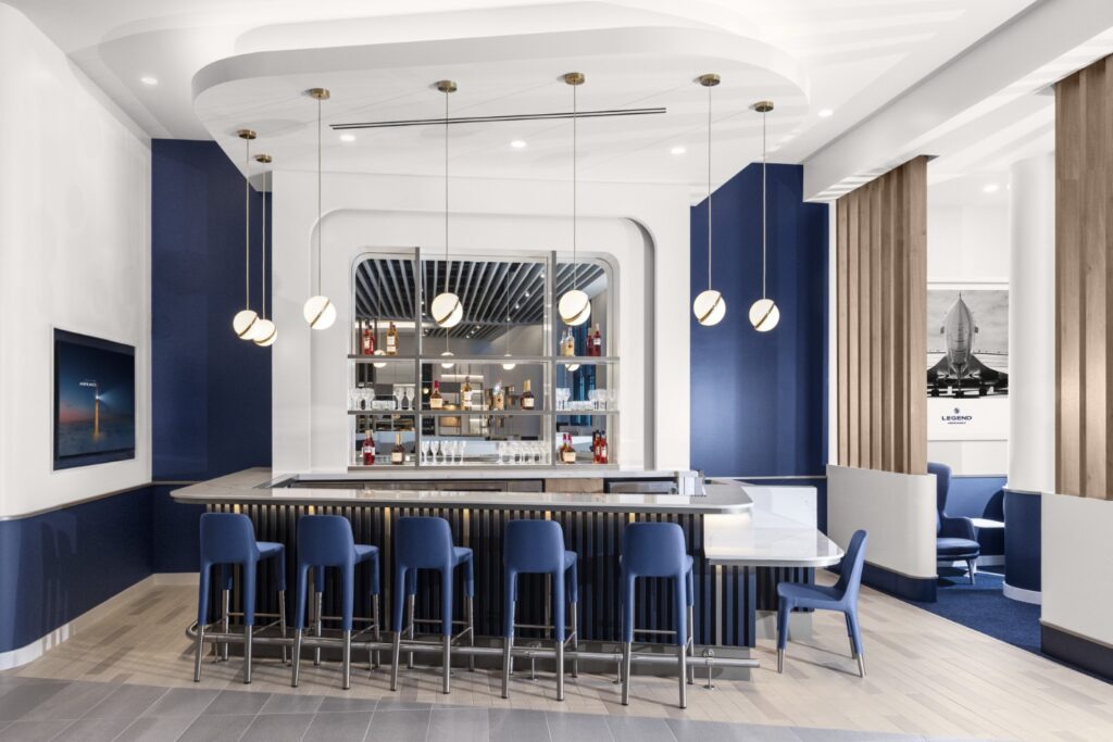 A bar is situated in the Air France lounge with high and low seating around different sides of it. 