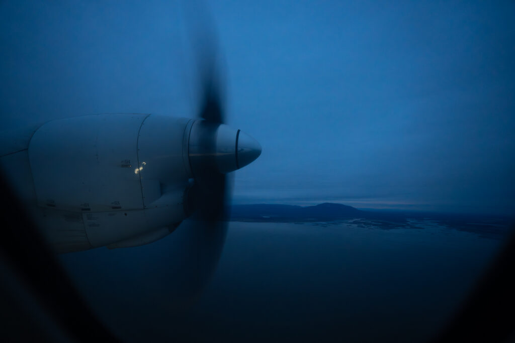 Aleutian Saab 2000 turboprop is seen from the aircraft window at night over the water.