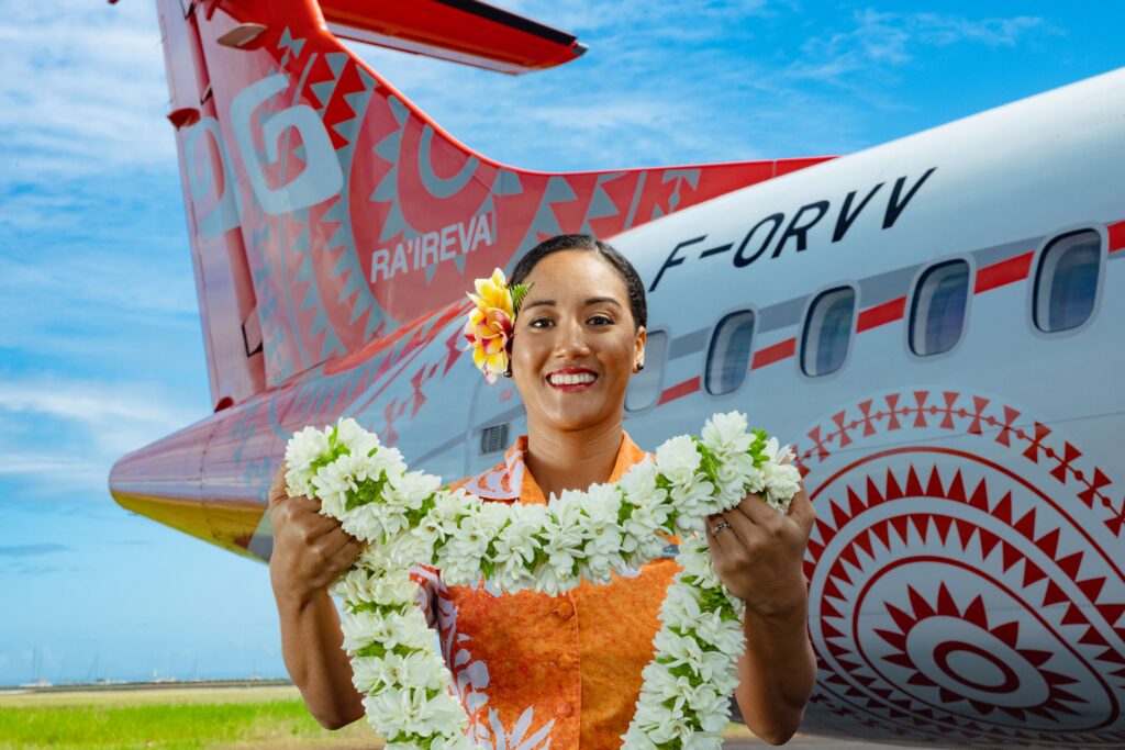 Air Tahiti crew member welcoming a passenger with a lei.