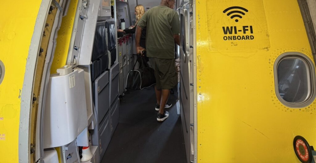 Entering the Spirit Airlines yellow aircraft with a Wi-Fi logo near the door.