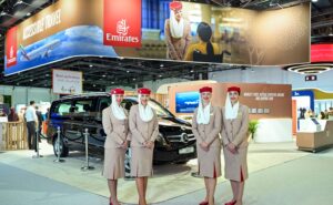 Emirates' stand at the 7th edition of AccessAbilities Expo in Dubai World Trade Centre with 4 flight crew members in uniform standing in front of it.