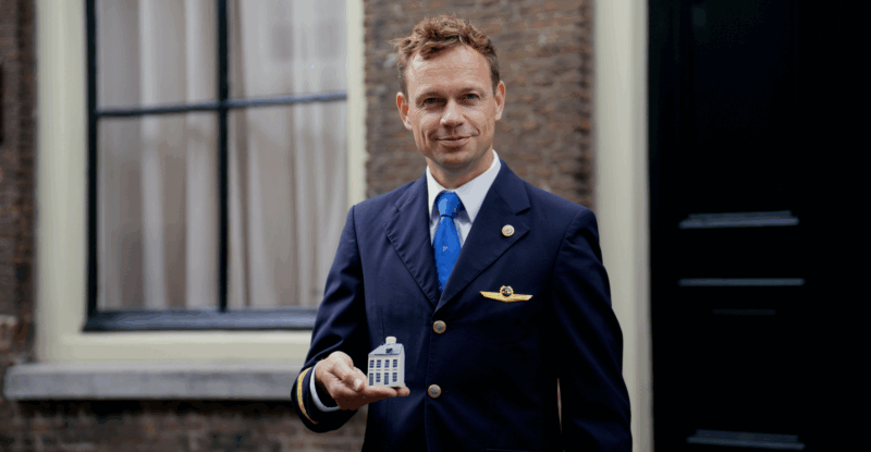 KLM crew member holding the Delft Blue House.