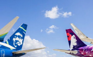 The tails of a Alaska Airlines and Hawaiian Airlines aircraft side by side.