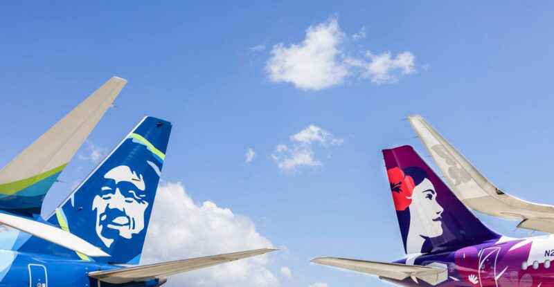 The tails of a Alaska Airlines and Hawaiian Airlines aircraft side by side.