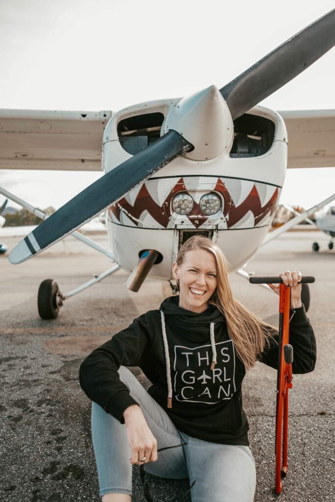 Christine Hannon posing for a photo in front of an aircraft with painted-on shark teeth.