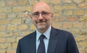 Luigi Celmi, CEO of Lufthansa Systems India is posing for a photo with a brick wall back drop.