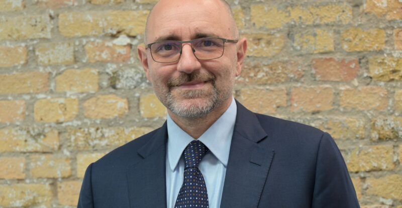 Luigi Celmi, CEO of Lufthansa Systems India is posing for a photo with a brick wall back drop.