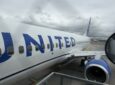 Looking down the side of the United Airlines aircraft while it is parked at the gate for boarding.