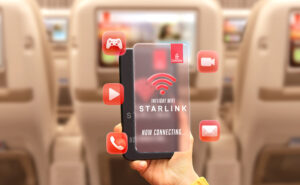 A passenger holds up their device in front of the Emirates IFE. The device says Starlink