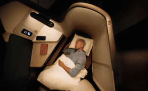 A passenger is asleep in the lie-flat seat onboard an aircraft.