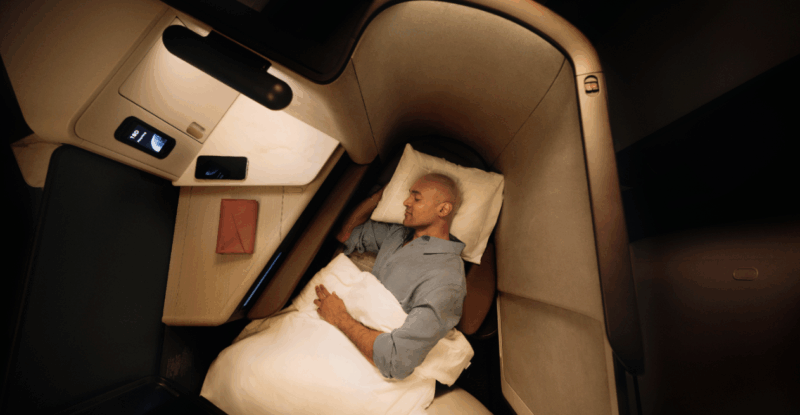 A passenger is asleep in the lie-flat seat onboard an aircraft.