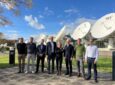 Various members of the SES team standing together in front of satellite dishes.