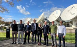 Various members of the SES team standing together in front of satellite dishes.