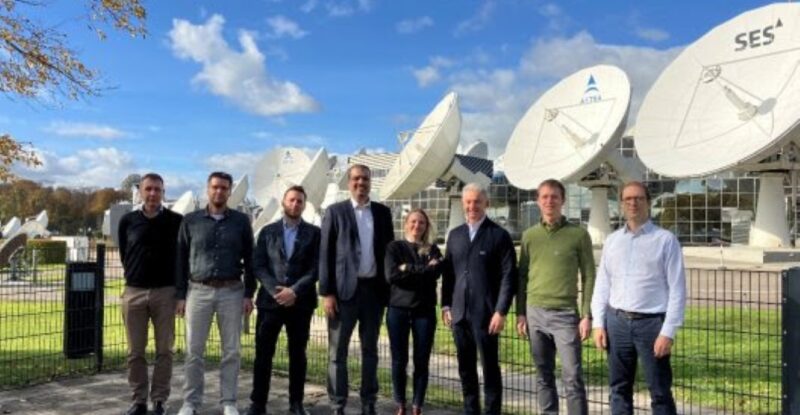 Various members of the SES team standing together in front of satellite dishes.