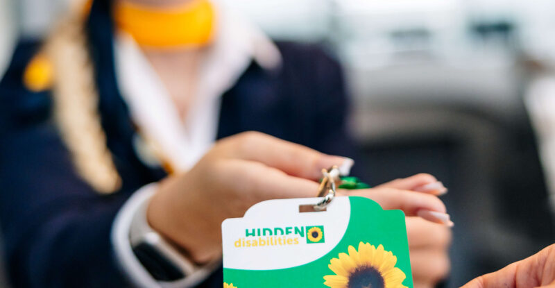 A Lufthansa crew member is handing the sunflower lanyard to a passenger