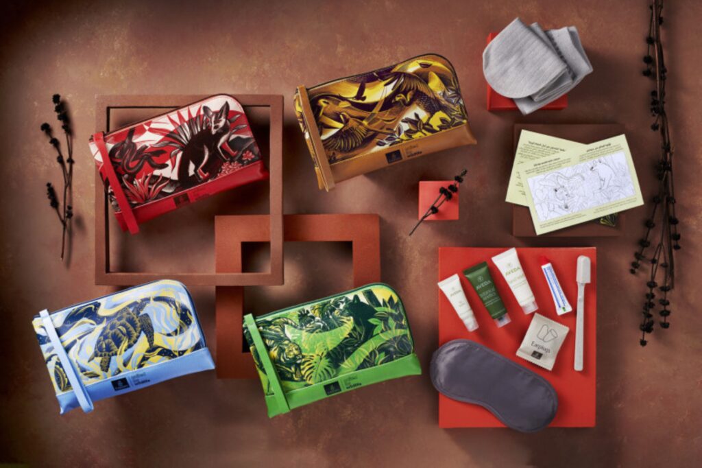 Four amenity kit designs are situated on a brown table with the contents laid out next to them.