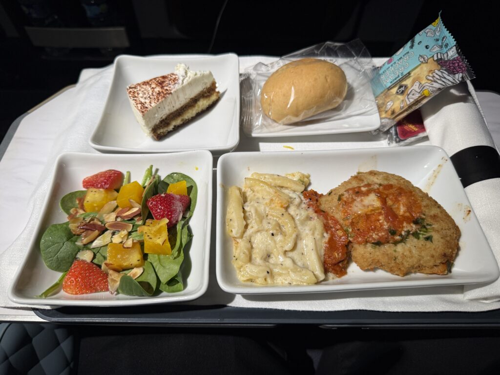 Chicken parmigiana with fettuccini alfredo, served with a salad featuring strawberries and almonds.
