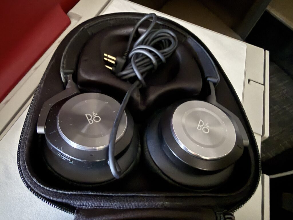 Bang & Olufsen headphones are displayed on the tray table. 