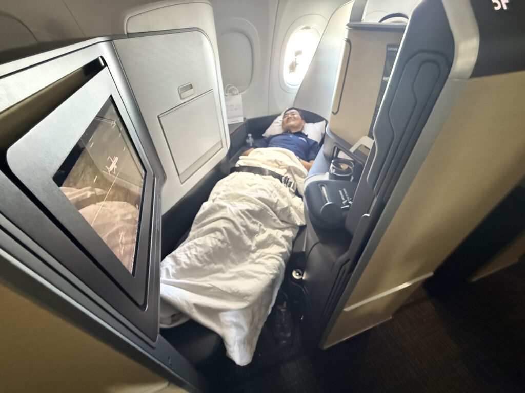 A man is laying in the American Airlines Airbus A321XLR Flagship Suite all tucked in.