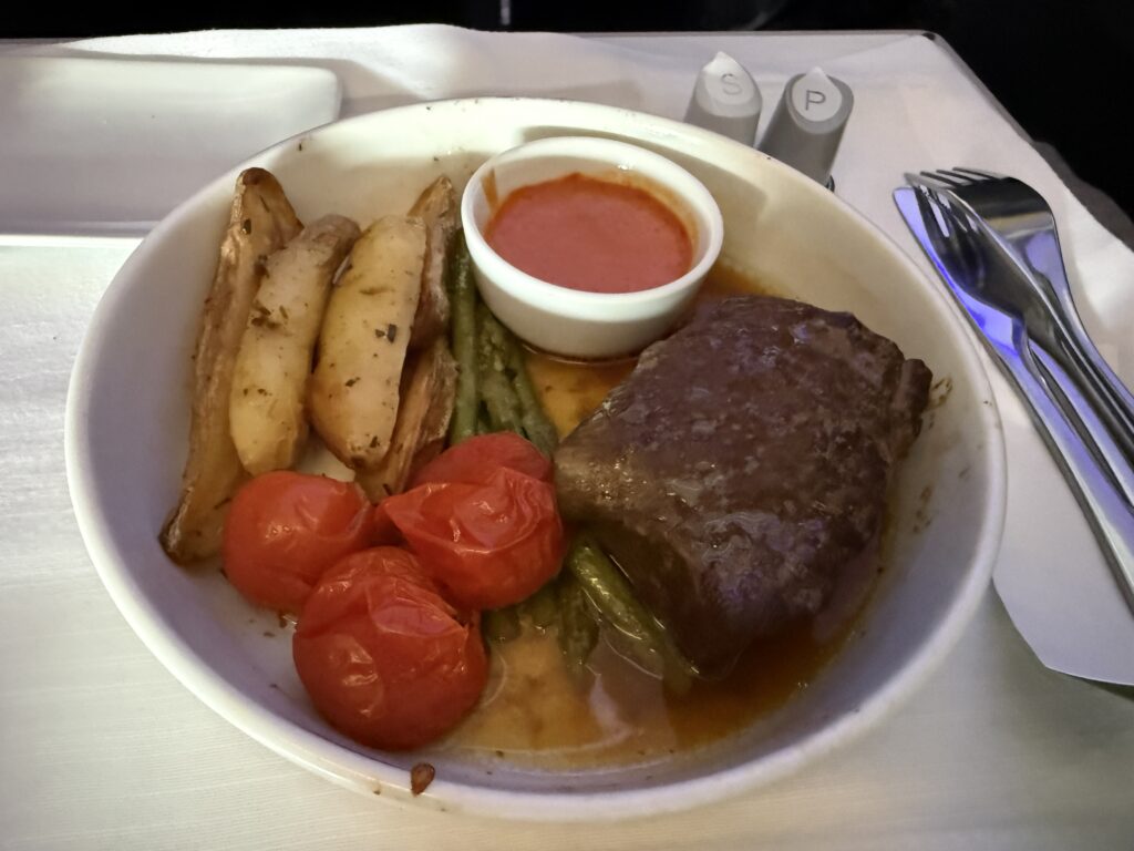 Short rib with veggies is served in a sauce. 