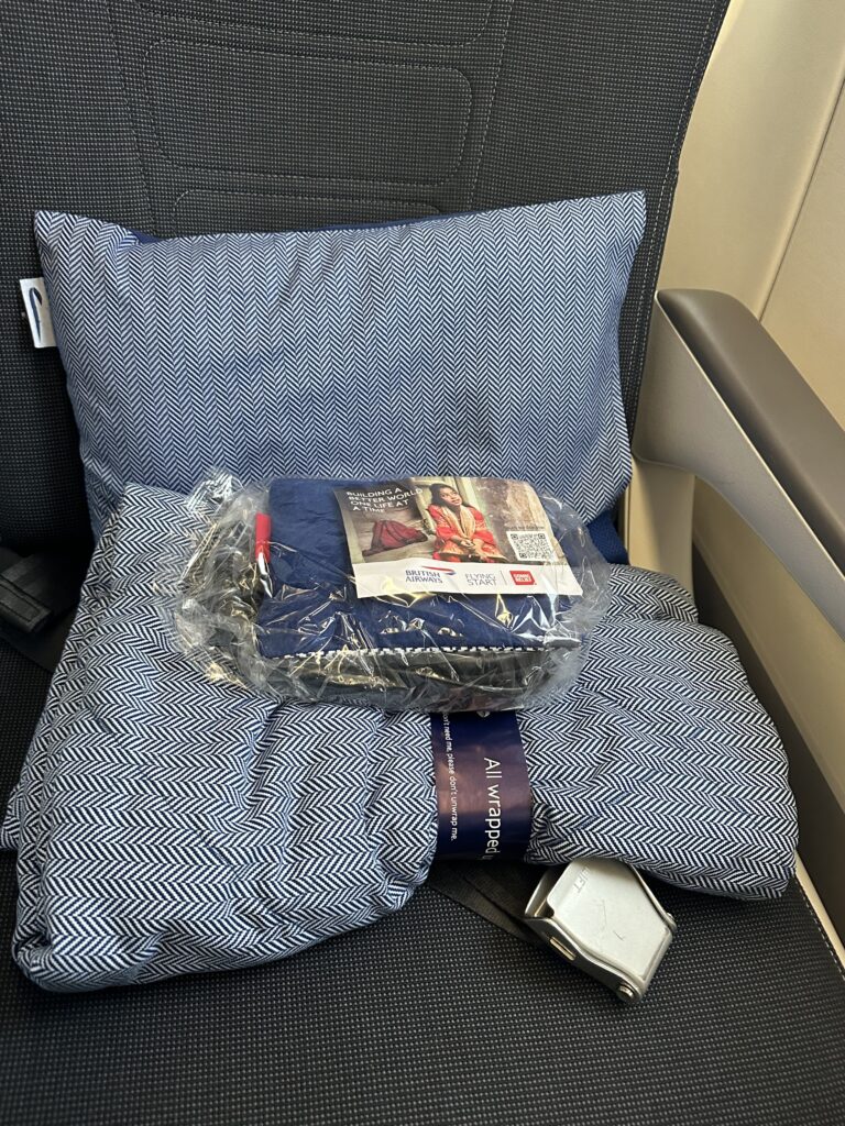 A quilt and a large pillow await the PE passenger on their seat.