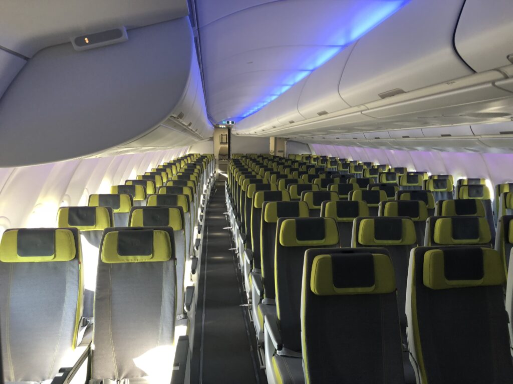 TAP's economy class cabin on the A330neo with Recaro seats in grey and green and grey headrests.
