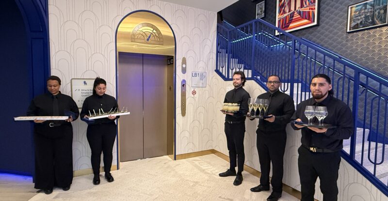 BlueHouse lounge staffers welcome guests with beverages at the entrance