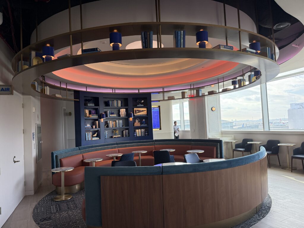 A large circular area for passengers to relax. There is a book wall and a book display hanging from the ceiling.