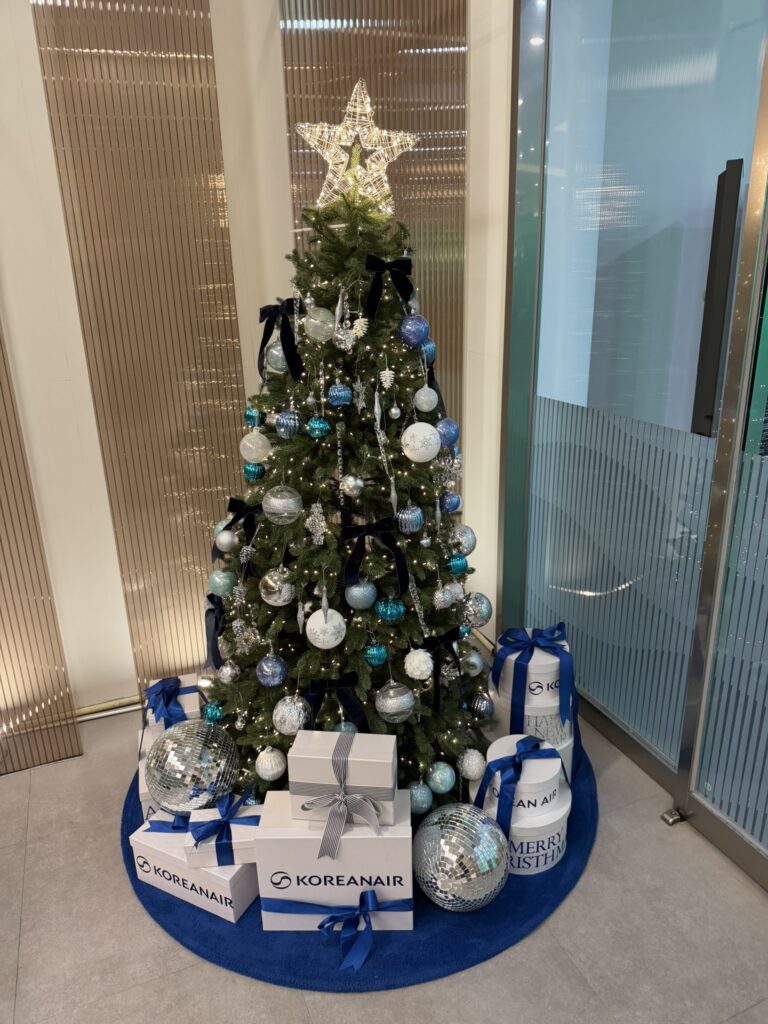 A Christmas tree decorating a corner of the airport lounge. With Korean Air branded gifts under it.