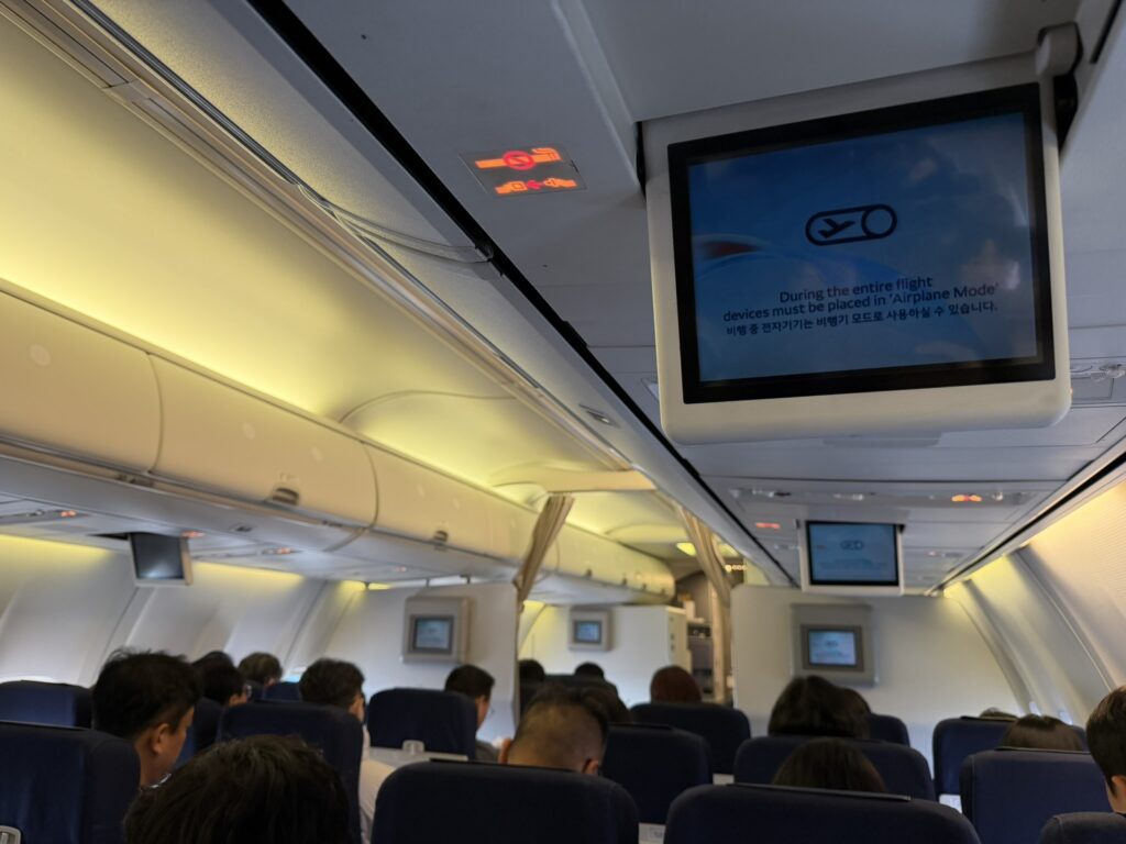 Inside the Korean Air 737-900 where overhead video monitors are prevalent.