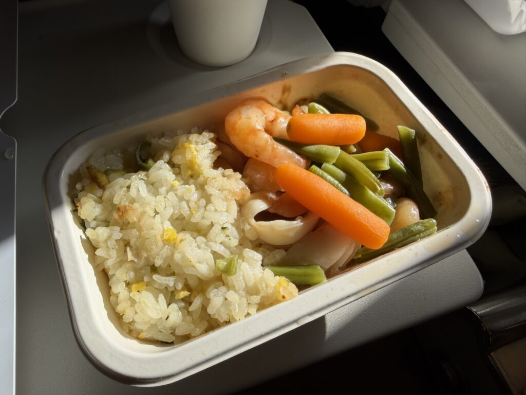Korean Air meal of shrimp, veggies and rice displayed on the aircraft tray table.