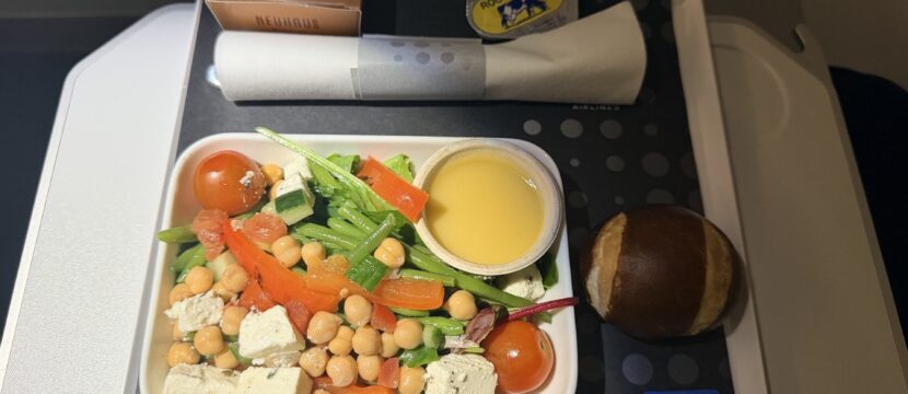 The passenger displays his meal consisting of a chickpea salad and pretzel bun.