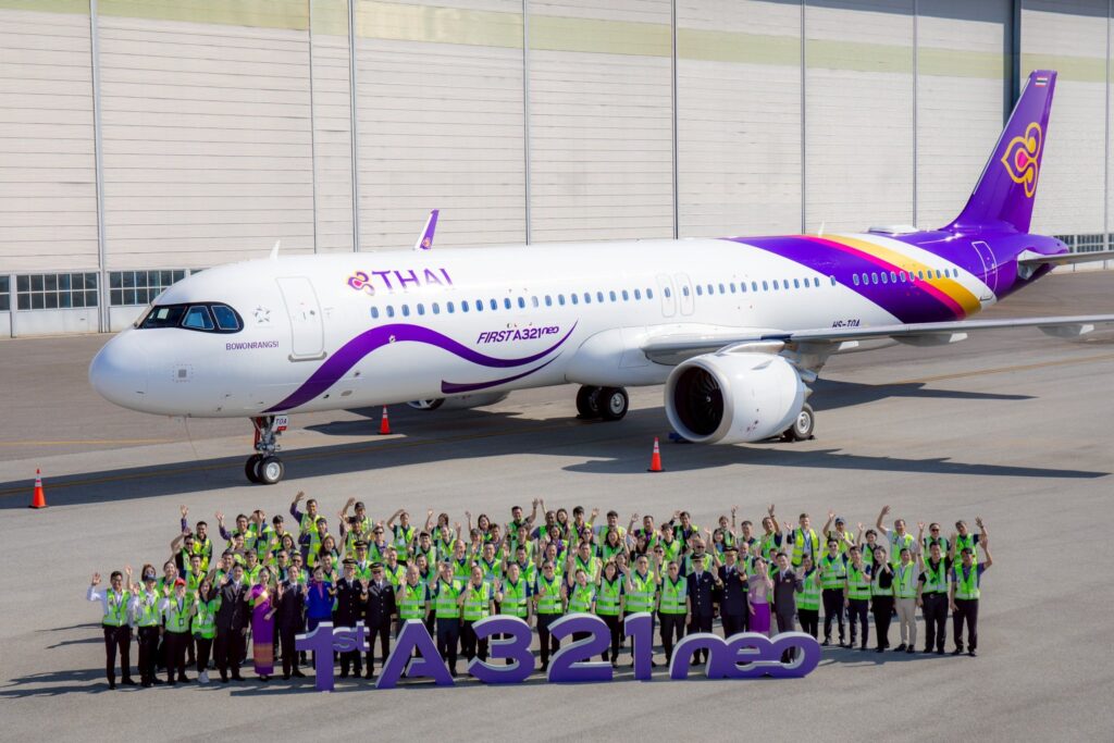 A large group of Thai Airways employees standing in front of the new A321neo, with an antenna hump clearly visible.