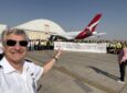 The Qantas A380 is at a hangar. Various members of the Qantas team are holding a banner and posing for a photo in celebration.