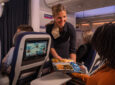 A Brussels Airlines crew member is handing a meal to a passenger.