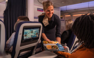 A Brussels Airlines crew member is handing a meal to a passenger.