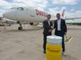 Jens Fehlinger, CEO of SWISS, and Philipp Furler, Co-CEO and Co-Founder of Synhelion, celebrate the long-term SAF offtake agreement while shaking hands behind a fuel barrel and in front of a SWISS aircraft.