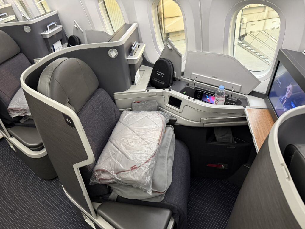 Items including a blanket, pillow and PJs are sitting on top of the business class seat for passengers when they board.