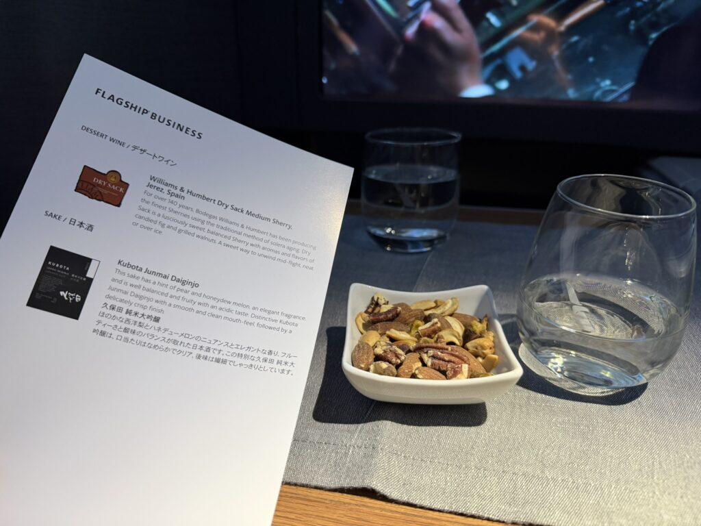 Menu page showing wine and sake options sits beside a bowl of nuts.