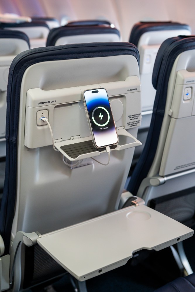 A mobile device is charging while situated on the in seat PED holder.