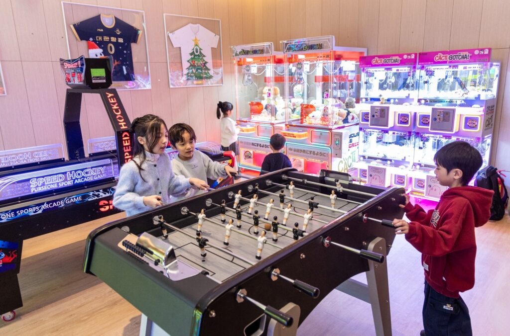Young passengers are playing foosball in the Arcade Room entertainment zone.