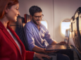 Two passengers are looking at a laptop in flight.