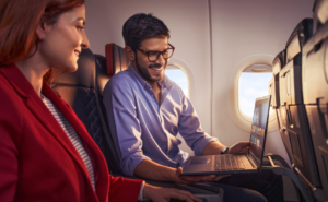 Two passengers are looking at a laptop in flight.