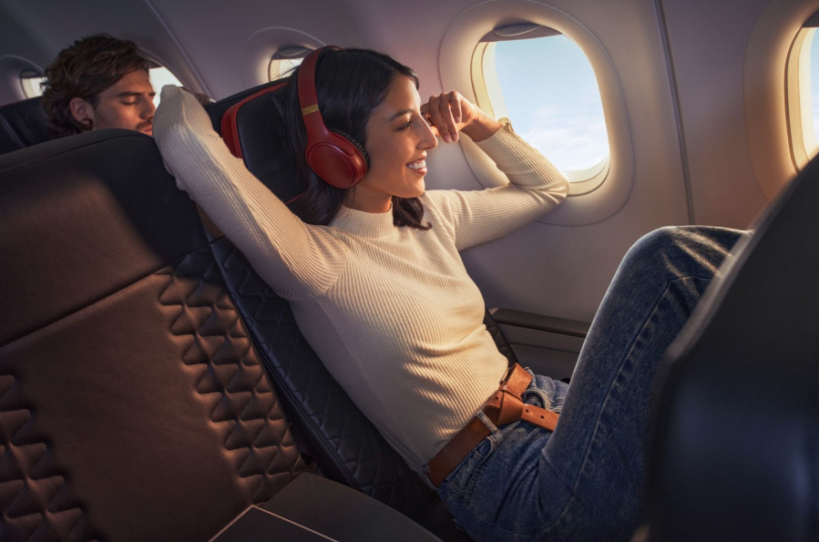 Avianca passenger is sitting relaxed legs up in a slightly reclined position looking out the aircraft window.