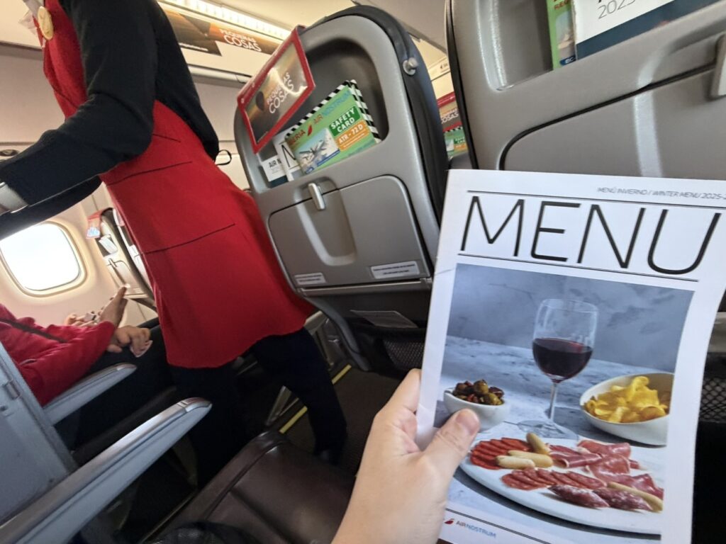 A passenger is holding up the buy-on-board menu for Iberia. 
